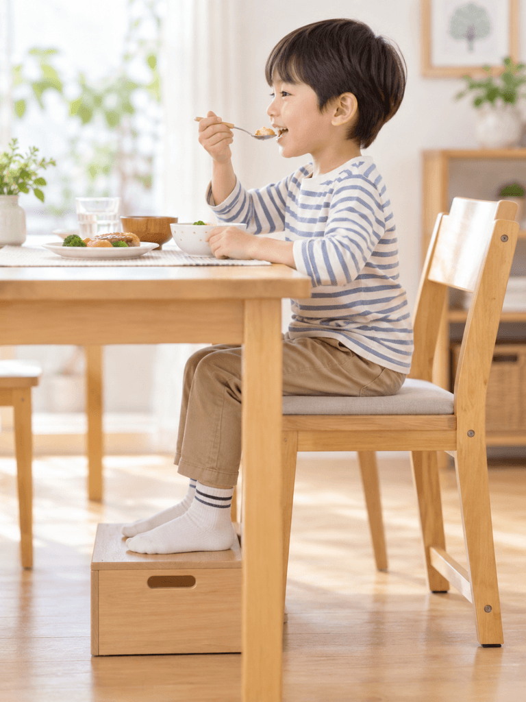 足台に足をしっかりのせて安定した姿勢で食事をする男の子の写真
