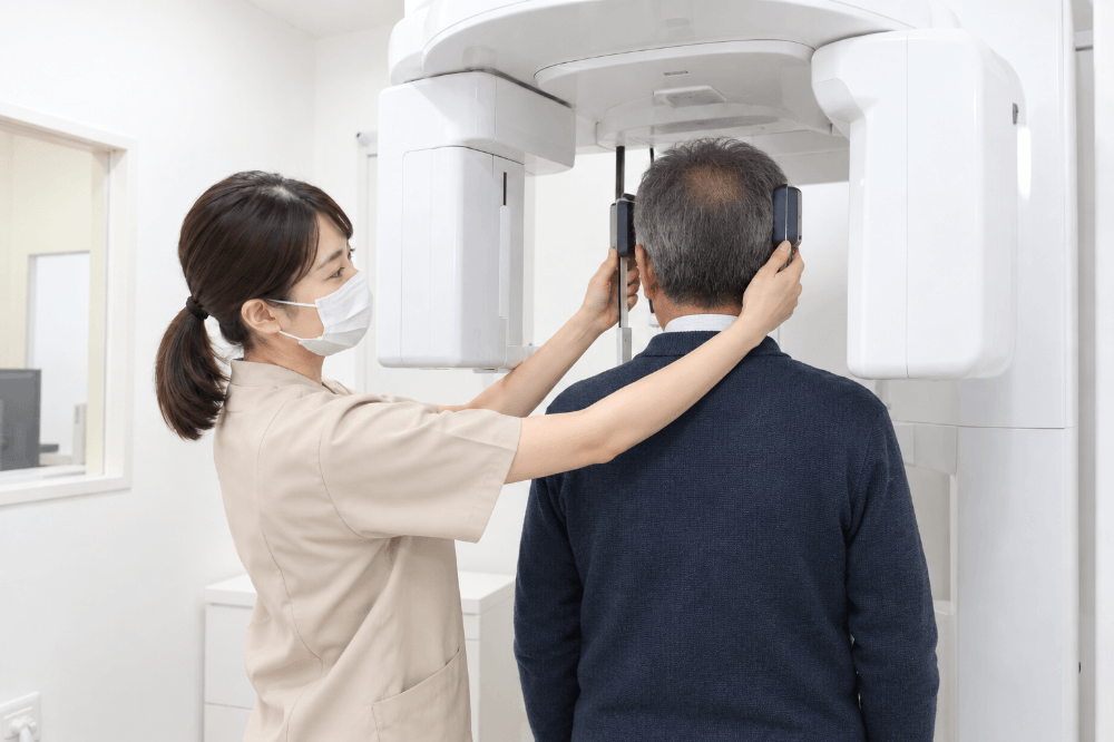 歯科用CT装置の中に立った患者さんの位置を、スタッフが合わせている撮影前の様子