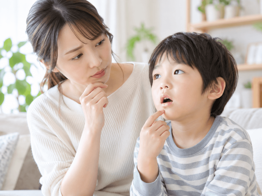 お子さんの口元を見ながら相談する母親と男の子の写真