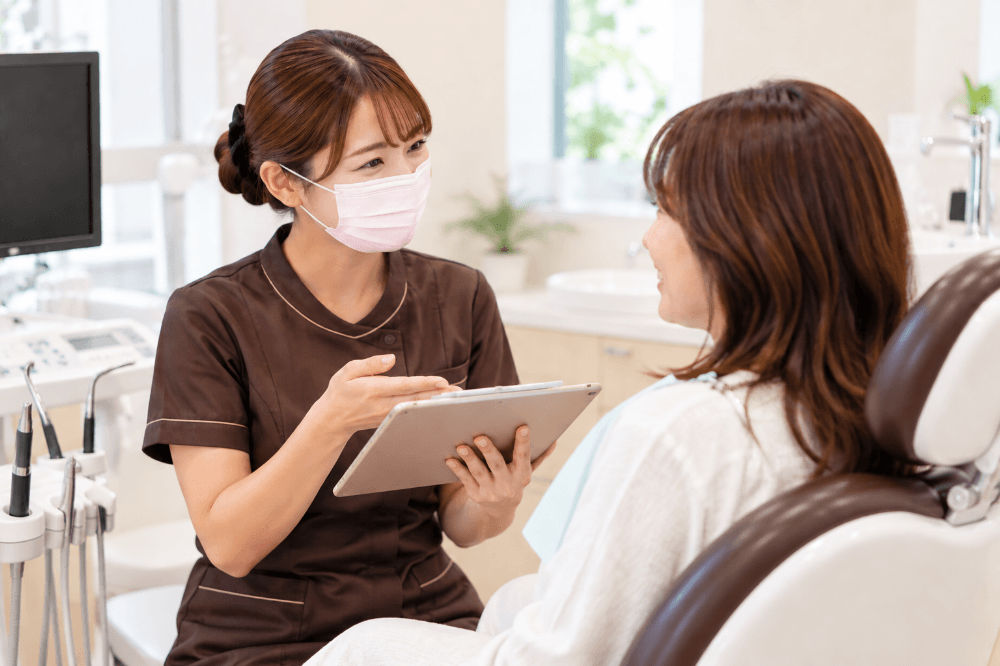 定期メインテナンスを終えた患者さんと歯科衛生士が、笑顔で次回の予定を話している様子
