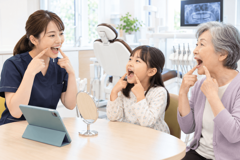 歯科衛生士がお子さんと高齢の方にお口の機能の練習を指導する様子